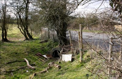 11TO012
The water flowed under the road at the entrance to Ash Park and down the valley to Ashe crossroads. Old culverts there show that such flooding is not a new problem. Using these culverts the water crosses the road again and joins the small lake which is the official source. Photo March 2006. 

By Tony Morris
