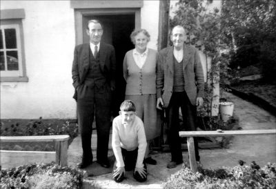 13_2TL001_06
Frederick Smith Mr and Mrs Shadwell (Jim and Flo) and young John Frederick Smith outside a cottage on The Lynch - c.1964 

From Barry Shadwell
